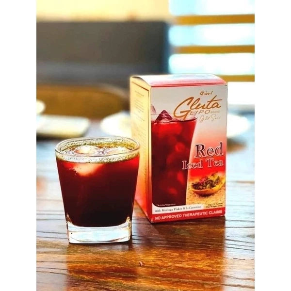 Glass of red tea next to a box of Red Iced Tea on a wooden surface.